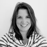 Smiling woman with shoulder-length hair, wearing a striped top. The black-and-white photo conveys a friendly, approachable feeling.