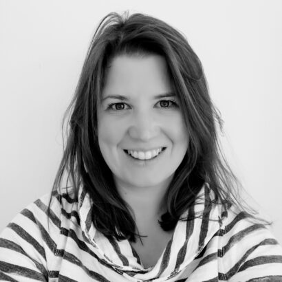 Smiling woman with shoulder-length hair, wearing a striped top. The black-and-white photo conveys a friendly, approachable feeling.