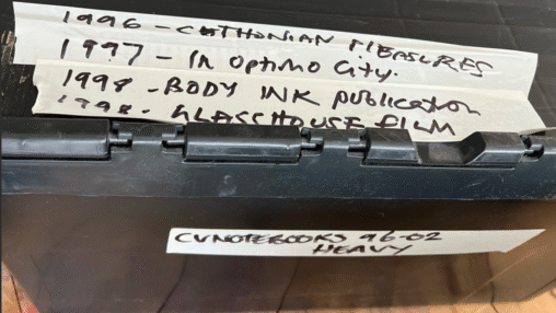 A black storage box labeled with dates and titles