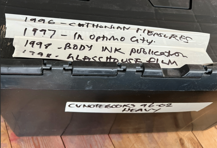 A black storage box labeled with dates and titles