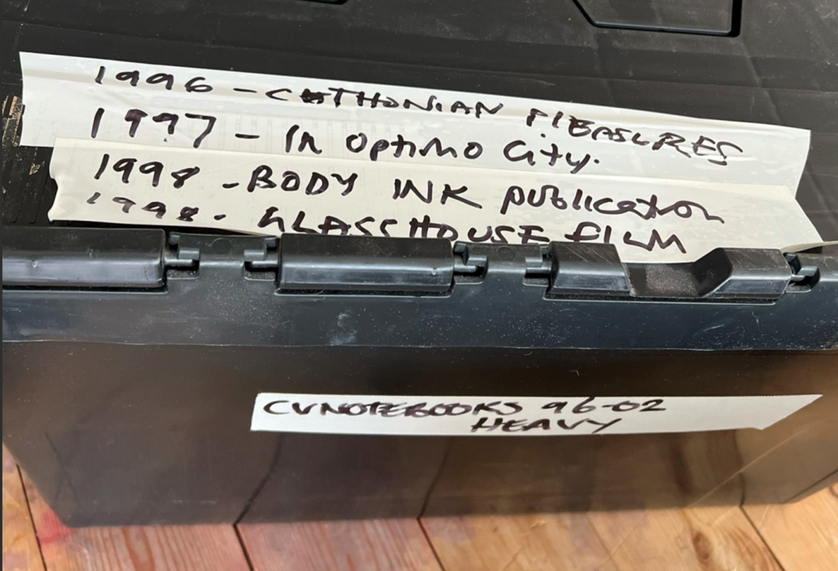 A black storage box labeled with dates and titles